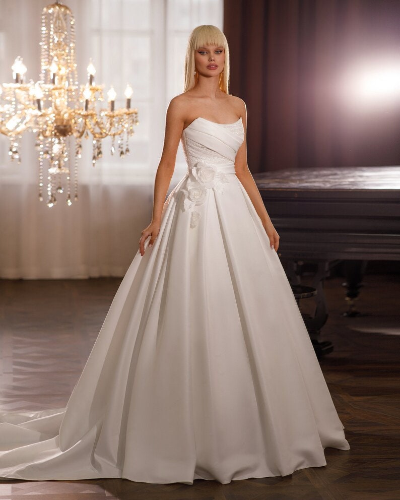 Beautiful Strapless Shimmering Scoop Neck Underlay With Pleated Satin Overlay And Shimmering 3D Flower Waistline Detail A-Line Gown