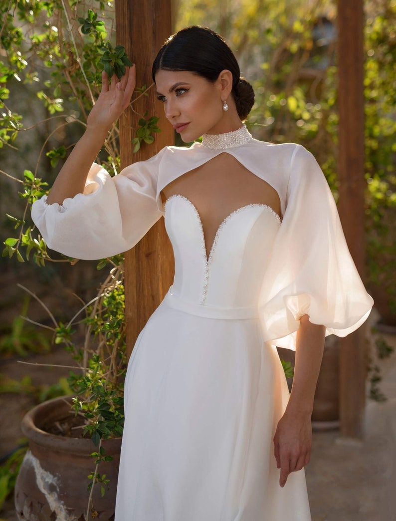 beaded bolero for wedding dress delicate beaded straps meet a sculpted bodice and basque waist for that regal fit. Add the lace bolero with flared sleeves, and Silvia turns from princess dream into couture statement Silvia