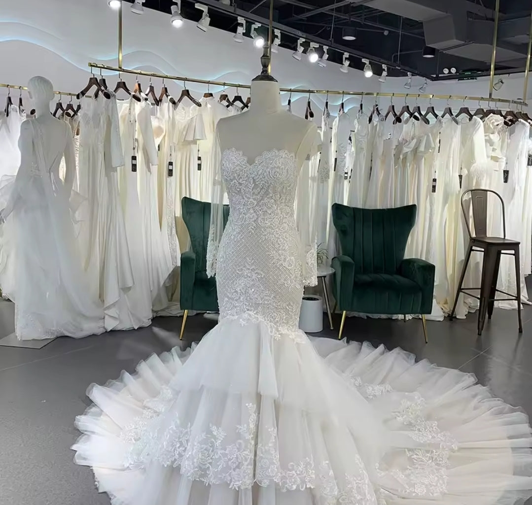 Long Sleeve Illusion Sleeve And Neckline Lace Sweetheart Fit To Flare Bridal Gown With Multi Layered Tiered Skirt Hem And Button Up Enclosure